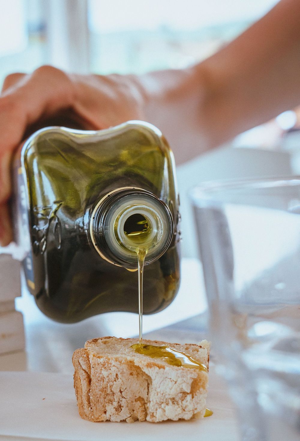 Extra virgin olive oil being poured over a slice of bread.