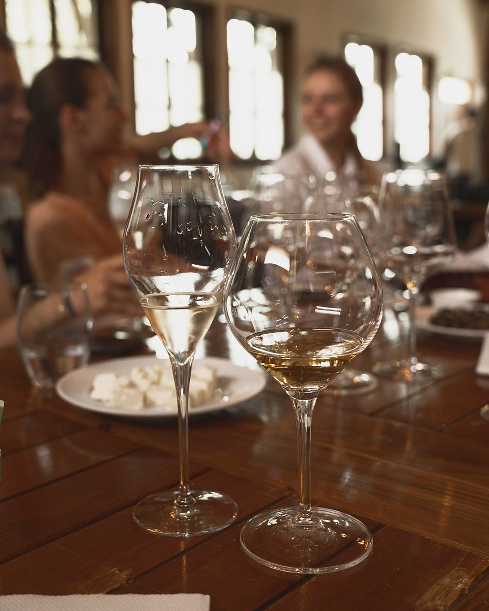 Two glasses of white wine on a wooden table during a tasting.