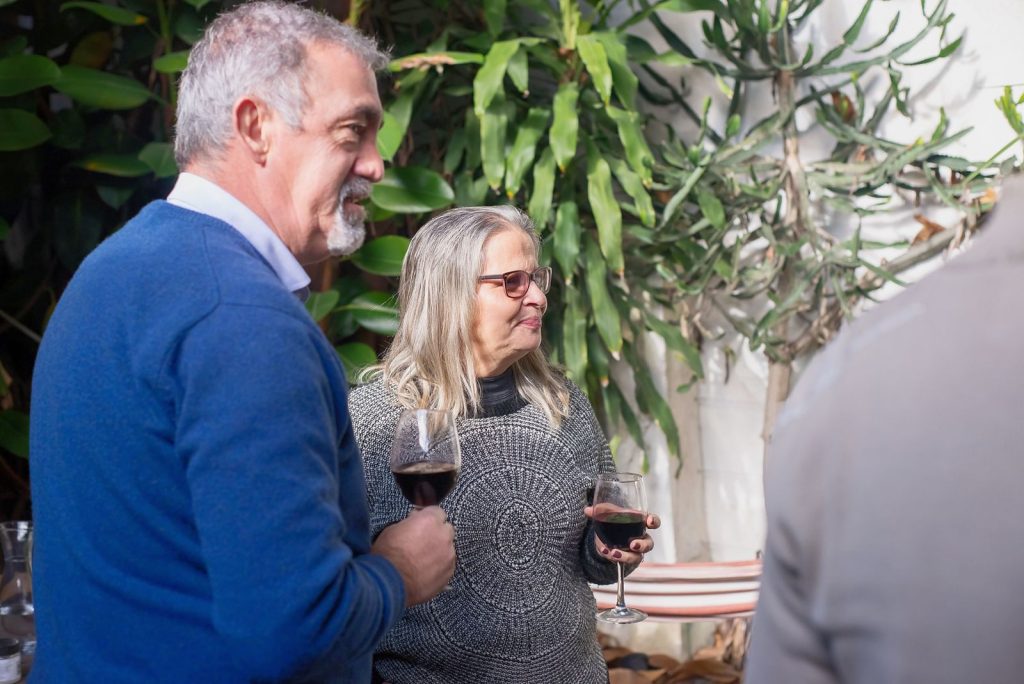 A couple enjoys a red wine tasting in a leafy courtyard.